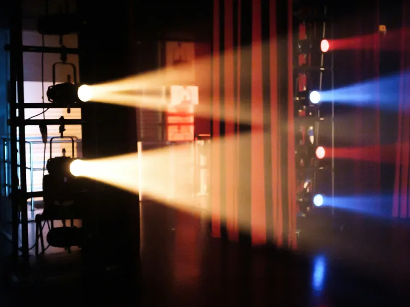 Amber stage lights cutting through a dark event space.